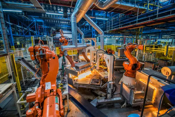 Factory with orange robotic arms, processing materials.