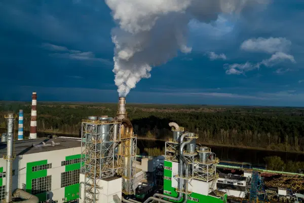 Manufacturing facility with exhaust pipe emitting clouds of smoke up into the air.